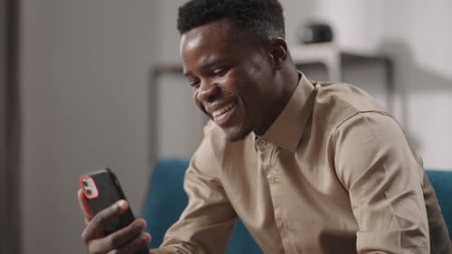 Happy Man Video Calling on Smartphone Laughing Indoors