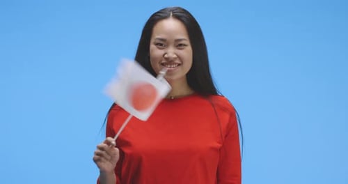 Junge Frau winkt mit japanischer Flagge