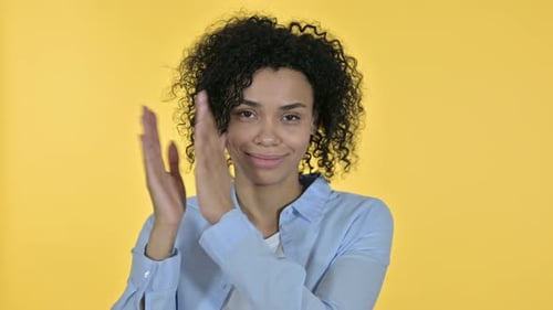 Smiling Woman Clapping Against Yellow Background