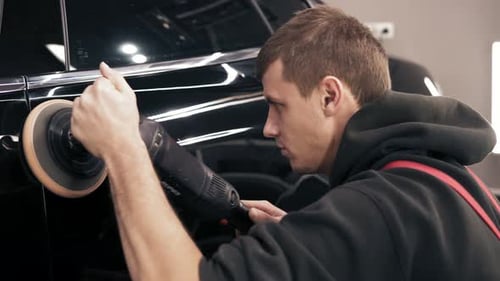 Man Buffing Black Car in Auto Shop