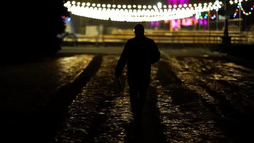 Silhouette Walking at Night with Festive Lights