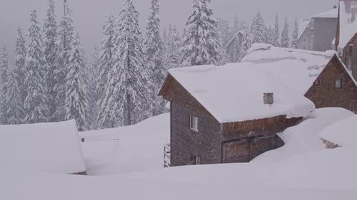 Camera Pan Over a Village in the Mountains Covered in Snow During a Heavy Snowfall