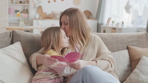 Mother and Child Reading Heart Card on Sofa