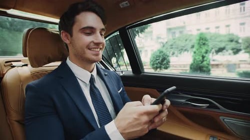 Smiling Man Uses Smartphone in Luxury Vehicle
