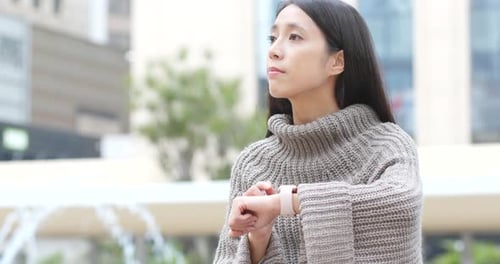 Woman Uses Smartwatch in Urban Setting