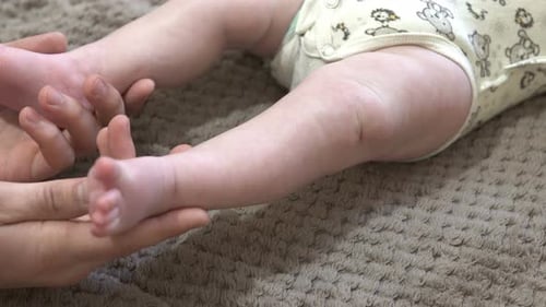 A young dad caresses his child's feet.