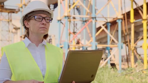 Female foreman at construction site working on laptop