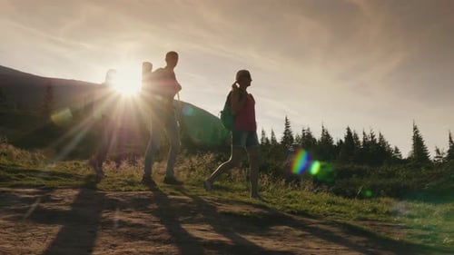 Towards Adventure - Friends with Backpacks Walk Along the Mountain Path at Sunset