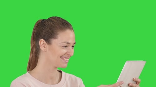 Young Cheerful Woman Is Using Tablet on A Green Screen, Chroma Key.