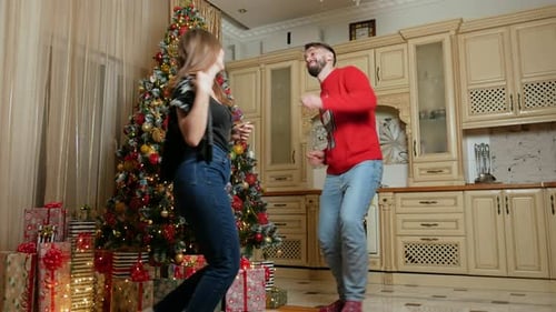 Couple Dancing Merrily by Christmas Tree in Kitchen