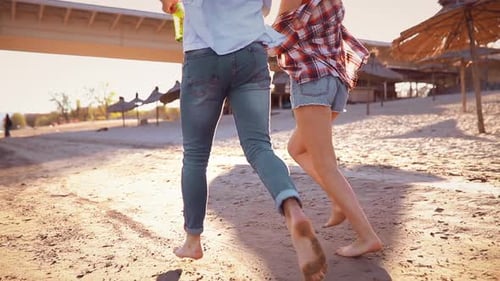 Carefree Couple in Love Running Barefoot on Beach