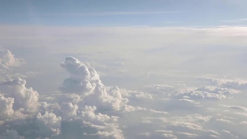 Airplane flying above clouds with a blue sky over the horizon
