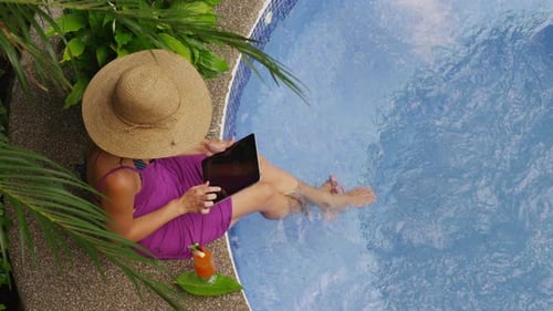 Woman Relaxing Poolside with Tablet in Tropical Setting