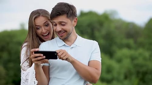 Smiling Couple Enjoying Smartphone Together Outdoors