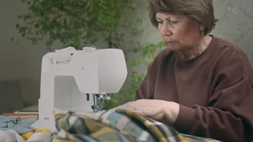 Woman Sewing Plaid Fabric at Home on Machine
