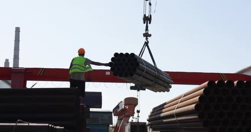 Crane Lifts Pipes in Industrial Outdoor Setting