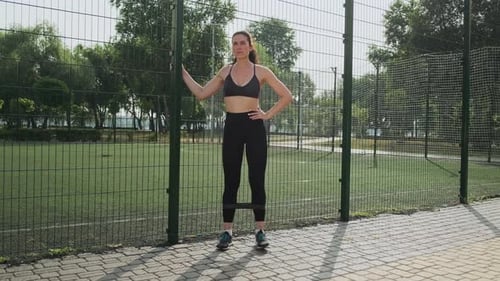 Young Woman in a Sporty Black Short Top and Gym Leggings Makes Lunges By the Feet Forward with Sport