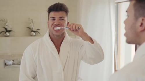 Man Brushing Teeth in Bright Bathroom Mirror