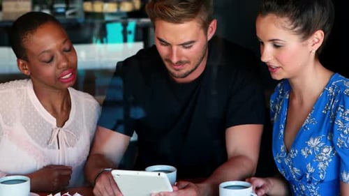 Three Friends Looking at a Tablet in Cafe