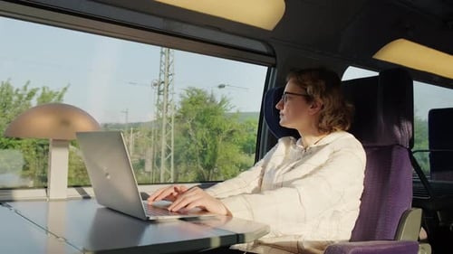 Femme travaille sur un ordinateur portable en train assis près de la fenêtre le jour ensoleillé