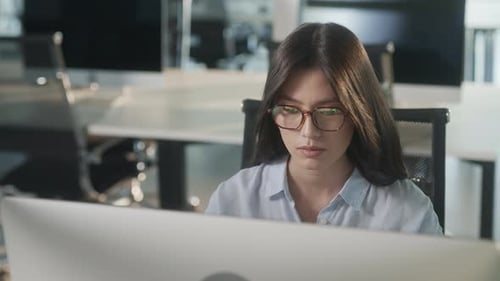 Young Asian Marketing Specialist Working on Laptop Computer in Busy Creative Office Environment