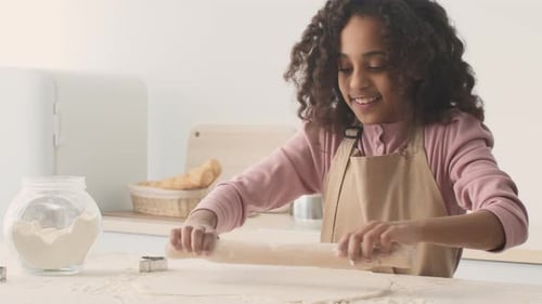 Close Up Portrait of Cheerful African American Girl Rolling Raw Dough with Pin Preparing Homemade