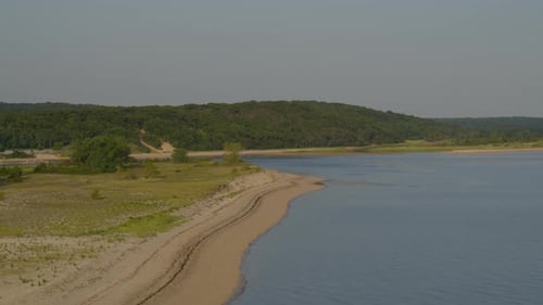 Forward Aerial Pan of a Sandy Beach Shore Near Dense Forest Trees