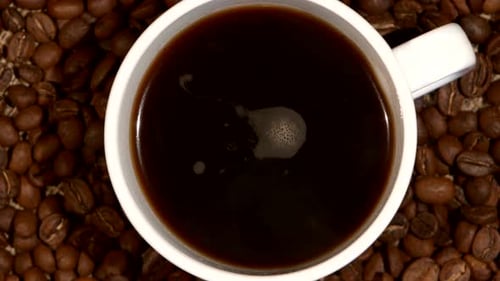 Weiße Tasse mit Kaffeeständer auf braunen Bohnen, Sackleinen, Nahaufnahme