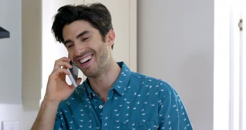 Man Smiling Talking on Mobile Phone in Kitchen
