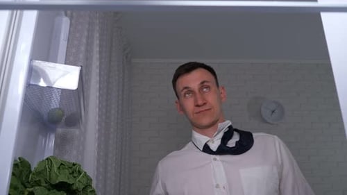 Man with Tie Looks at Items in Refrigerator