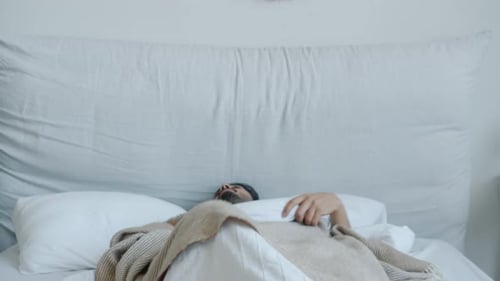 Man Wakes Up and Stretches in Bed