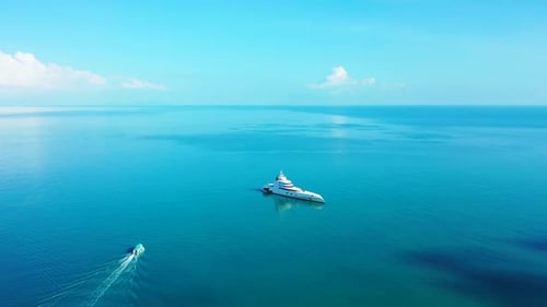 Lindo iate grande ancorando na calma lagoa azul turquesa e barco navegando perto da costa tropical