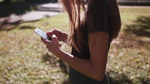 An Attractive Young Lady Using a Phone in Town. Medium Shot