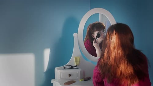 Woman Applying Makeup in Front of Mirror