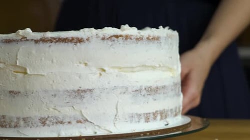 Close up of woman hands making sweet cake with white cream and biscuit.