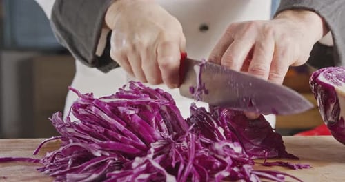 Zeitlupen-Nahaufnahme eines Kochmessers beim Schneiden eines Rotkohls