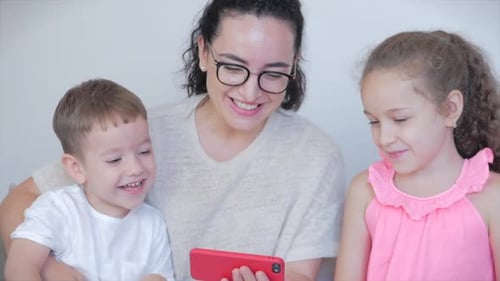 Mother and Children Laughing While Watching a Phone