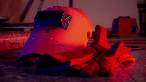 Welding Helmet and Gloves in Dark Workshop