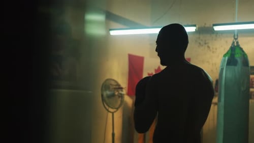 Boxer Shadow Boxing in Dark Indoor Gym at Night