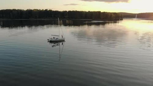 Young People in Love Hug Standing on the Bow of a White Yacht During a Calm on the Lake in the