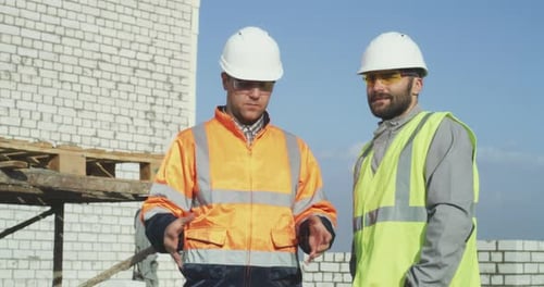 Construction Engineers Discussing Plans on Building Site