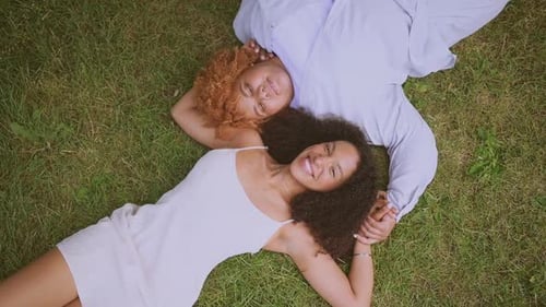 Two Women Smiling and Laying on Green Grass