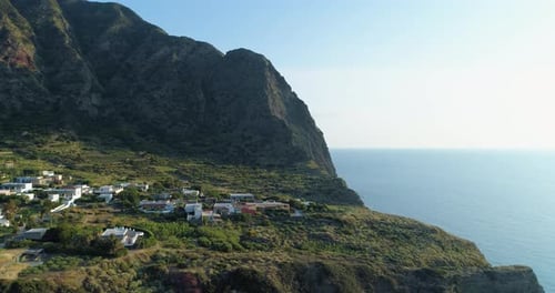 Littoral rocheux panoramique et pittoresque au coucher du soleil avec des champs verts, des arbres et un petit village