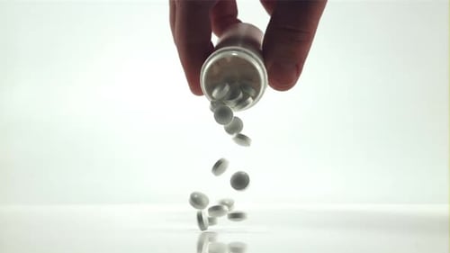 Pills Pouring from Prescription Bottle on White Surface