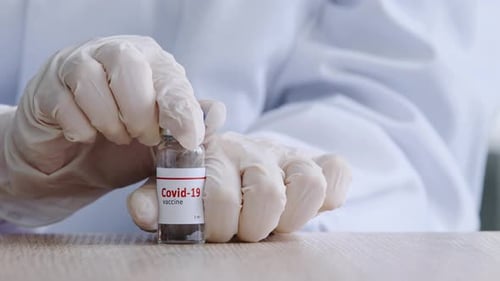 Gloved Hands Removing Cap from Covid-19 Vaccine Vial