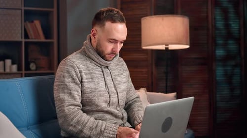 Man Using Laptop on Couch in Cozy Living Room