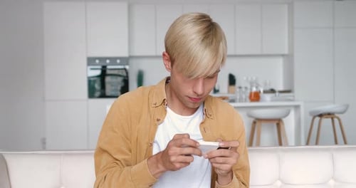 Young Man Using Smartphone in Modern Apartment