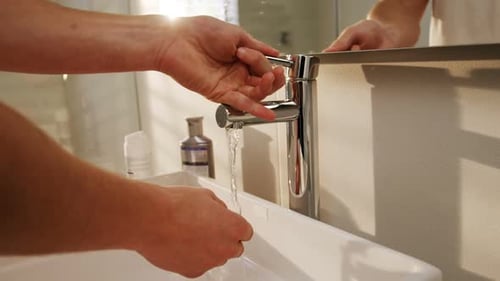 Man Washing Hands at Bathroom Sink