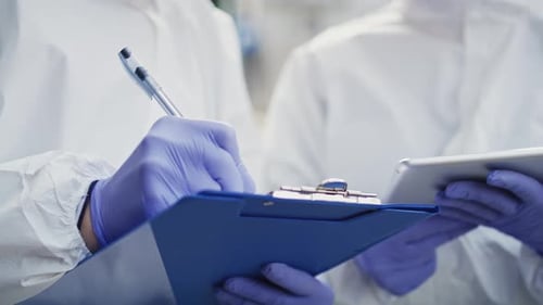 Scientists Wearing Protective Suits Taking Notes