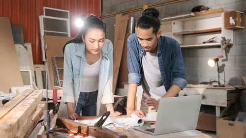 Carpenters Discussing Plans on Laptop in Workshop